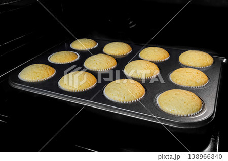 Homemade cupcakes, muffins baking and rising in electric oven Homemade cupcakes, muffins baking and rising in electric oven 138966840