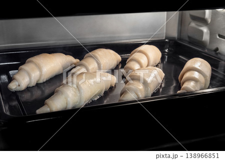 Six uncooked homemade croissants on tray in electric oven Six uncooked homemade croissants on tray in electric oven 138966851