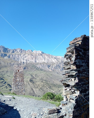 Ruins of the Kurta and Taga signal tower, North Ossetia, Russia. Crumbling stone walls of an ancient Alan watchtower on a green mountain slope 138967251