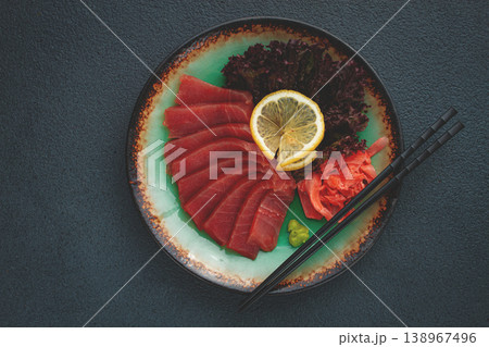 Fresh tuna sashimi served with lemon, wasabi, and pickled ginger on a dark background 138967496