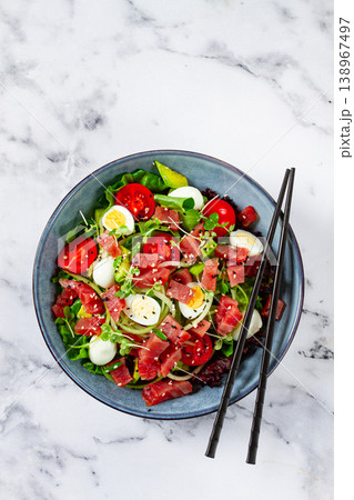 salad with fresh tuna, cherry tomatoes and quail eggs and avacado, served with chopsticks, 138967497