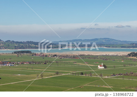 Countryside fields and lake with small church in Bavaria Germany under soft haze Countryside fields and lake with small church in Bavaria Germany under soft haze 138968722