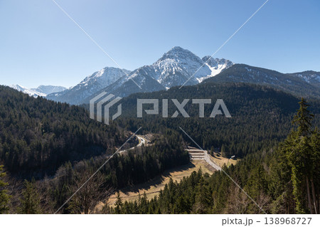 Snowcapped mountain above dense forest and winding road in Bavaria Germany Snowcapped mountain above dense forest and winding road in Bavaria Germany 138968727