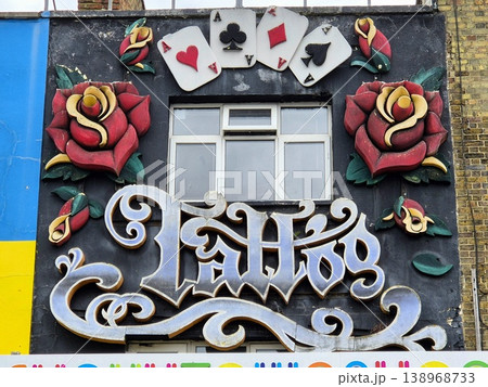 London uk 05.07.2025 tattoo shop facade with ornate lettering roses and playing cards decoration on building exterior showcasing vintage style urban street art and alternative culture atmosphere London uk 05.07.2025 tattoo shop facade with ornate lettering roses and playing cards decoration on building exterior showcasing vintage style urban street art and alternative culture atmosphere 138968733