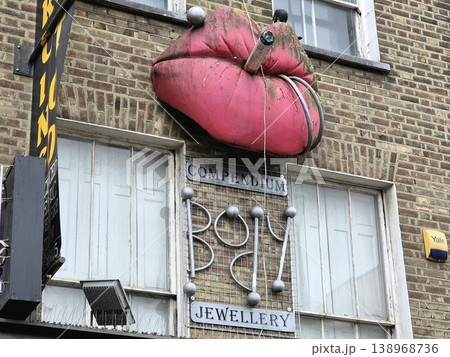 London UK 05.07.2025 Compendium jewellery shop facade with oversized lips sculpture and cigarette detail on brick building highlighting quirky design and creative urban street art in Camden area London UK 05.07.2025 Compendium jewellery shop facade with oversized lips sculpture and cigarette detail on brick building highlighting quirky design and creative urban street art in Camden area 138968736