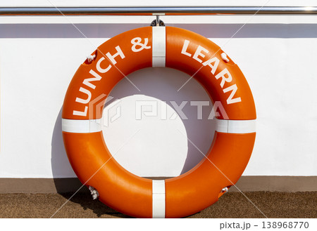 Lunch and learn symbol. Concept words Lunch and learn on beautiful orange lifebuoy. Beautiful white ship's board background. Business, educational and lunch and learn concept. Copy space. Lunch and learn symbol. Concept words Lunch and learn on beautiful orange lifebuoy. Beautiful white ship's board background. Business, educational and lunch and learn concept. Copy space. 138968770
