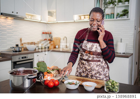 Woman chatting on phone while preparing healthy home cooked meal 138968891