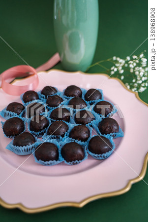 Chocolate truffles on pink plate with green background Chocolate truffles on pink plate with green background 138968908