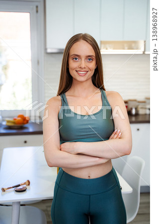 Young woman smiling in sports bra and leggings in kitchen Young woman smiling in sports bra and leggings in kitchen 138968927
