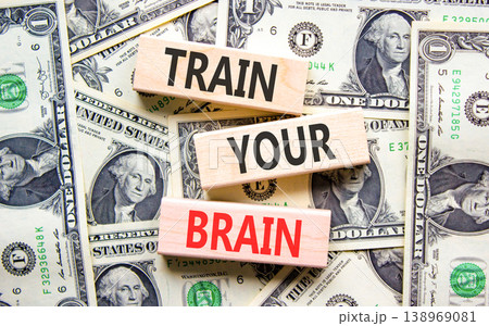 Train your brain words symbol. Concept words Train your brain on beautiful wooden blocks. Beautiful dollar bills background. Dollar bills. Business motivational and train your brain concept Copy space 138969081
