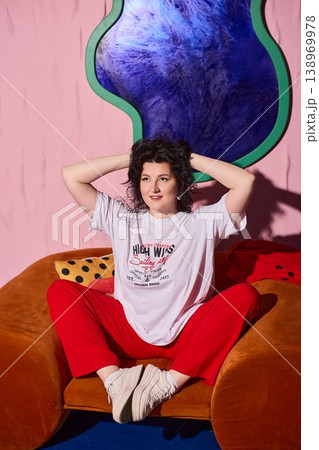 Woman sitting comfortably amidst bold colored decor and playful atmosphere 138969978