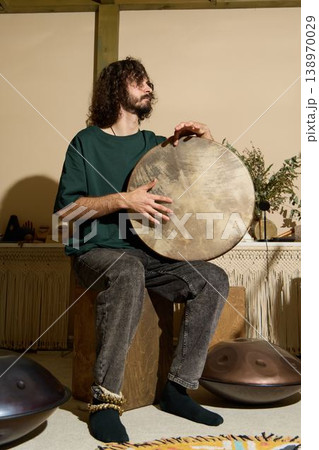 Caucasian musician with frame drum and handpan performing ambient set 138970029