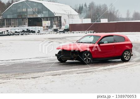 Driver maneuvers hatchback across snowcovered fields with smoke and marks Driver maneuvers hatchback across snowcovered fields with smoke and marks 138970053