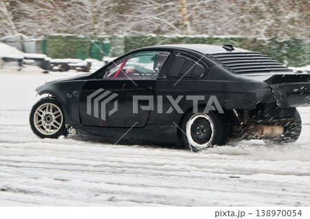 Black sports car skids through winter slush in tight turn 138970054