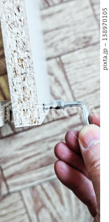 Tightening a screw in furniture assembled from flat parts manually using an Allen key. 138970105