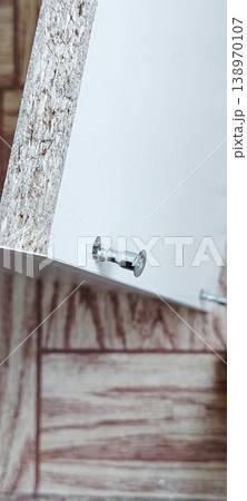 Close up of screwing a cam lock screw into a flat pack furniture panel. Close up of screwing a cam lock screw into a flat pack furniture panel. 138970107