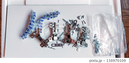 Furniture assembly hardware parts are scattered across the white panel. 138970109