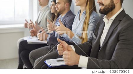 Group of business people sitting in row, giving thumbs up and positive feedback to speaker. 138970501