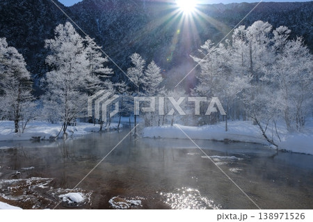 朝日に輝く霧氷の森と水面から立ち上がる蒸発霧 サンバーストが照らす幻想的な冬の池 朝日に輝く霧氷の森と水面から立ち上がる蒸発霧 サンバーストが照らす幻想的な冬の池 138971526