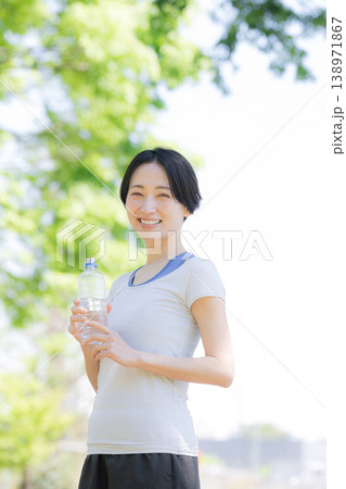 新緑の屋外で水分補給をする女性の横顔ポートレート　ウォーキングやランニングの運動 138971867