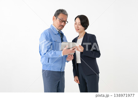 作業着でタブレットを持つ男性とビジネスウーマン 作業着でタブレットを持つ男性とビジネスウーマン 138971977