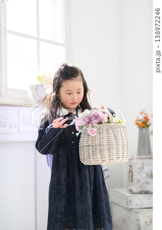 ランドセルを背負って花の入ったカゴを眺める日本人の女の子 ランドセルを背負って花の入ったカゴを眺める日本人の女の子 138972246