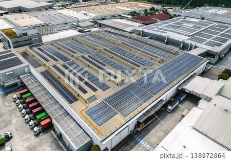 Solar-powered warehouse facility with freight trucks at loading docks. Eco-friendly logistics and efficient cargo transportation. Solar panels and sustainable energy concept in distribution center. 138972864
