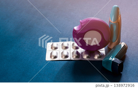 Set of asthma inhaler accuhaler and anti allergy pills on blue table, medical treatment for respiratory disease. Bronchodilator and steroid drugs for severe asthma control and relief in healthcare. Set of asthma inhaler accuhaler and anti allergy pills on blue table, medical treatment for respiratory disease. Bronchodilator and steroid drugs for severe asthma control and relief in healthcare. 138972916