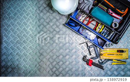 Toolbox and safety helmet on checkered metal plate background in workshop. Service tools set for construction, electrical and plumbing work, technician equipment. Repair and maintenance industry. Toolbox and safety helmet on checkered metal plate background in workshop. Service tools set for construction, electrical and plumbing work, technician equipment. Repair and maintenance industry. 138972919