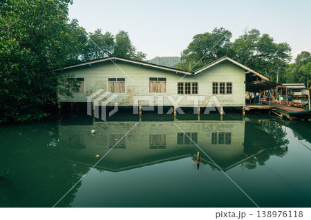 Traditional wooden boats and stilt houses along a calm canal surrounded by lush green mangrove forest. Traditional wooden boats and stilt houses along a calm canal surrounded by lush green mangrove forest. 138976118