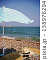 Beach umbrella and summer accessories on pebble beach by the sea 138976294