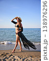 Woman walking on sandy beach in black bikini with flowing cover up 138976296