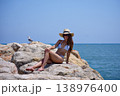 Woman relaxing on seaside rocks in bikini during summer vacation 138976400