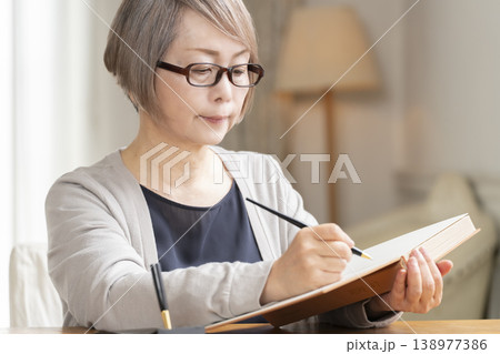 リビングでエンディングノートを書くシニア女性 138977386