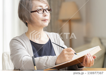 リビングでエンディングノートを書くシニア女性 リビングでエンディングノートを書くシニア女性 138977387