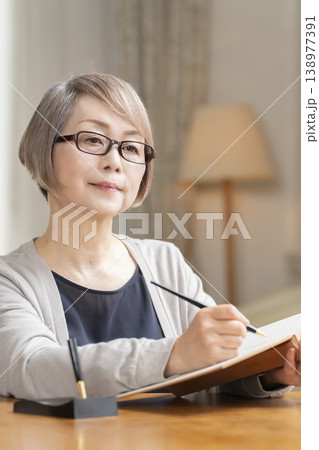 リビングでエンディングノートを書くシニア女性 138977391