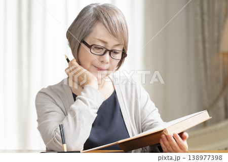 リビングでエンディングノートを書くシニア女性 リビングでエンディングノートを書くシニア女性 138977398