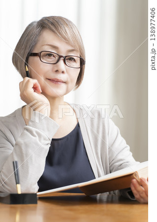 リビングでエンディングノートを書くシニア女性 リビングでエンディングノートを書くシニア女性 138977406