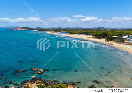 Aerial view of Rose Bay in Bowen, Queensland, Australia. The scene shows a tropical coastal landscape with clear blue water, sandy shoreline and surrounding natural environment. Aerial view of Rose Bay in Bowen, Queensland, Australia. The scene shows a tropical coastal landscape with clear blue water, sandy shoreline and surrounding natural environment. 138978293