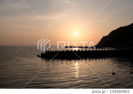 夕日を浴びて黄金色に輝く海面と山影・静寂に包まれる小さな漁港の黄昏風景 夕日を浴びて黄金色に輝く海面と山影・静寂に包まれる小さな漁港の黄昏風景 138980903