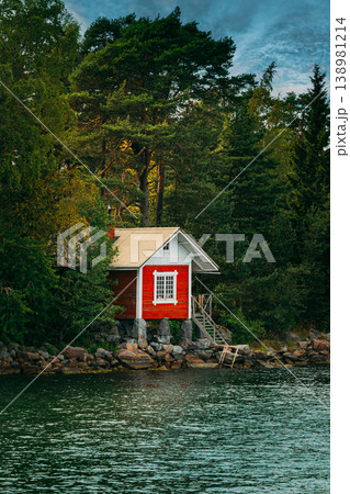 Traditional Red Cabin on a Rocky Shoreline Traditional Red Cabin on a Rocky Shoreline 138981214