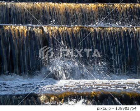 Water cascades down stone steps in golden sunlight 138982754