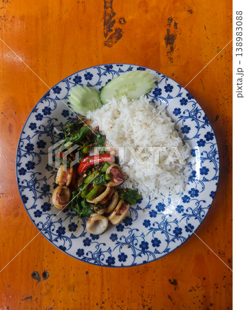 Thai Basil Squid Stir Fry with White Rice and Cucumber on Floral Plate Thai Basil Squid Stir Fry with White Rice and Cucumber on Floral Plate 138983088