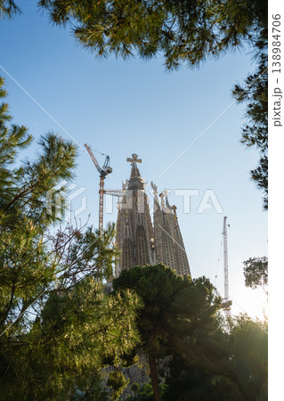 Sagrada Familia towers with construction crane and trees under blue sky in Barcelona Spain 138984706