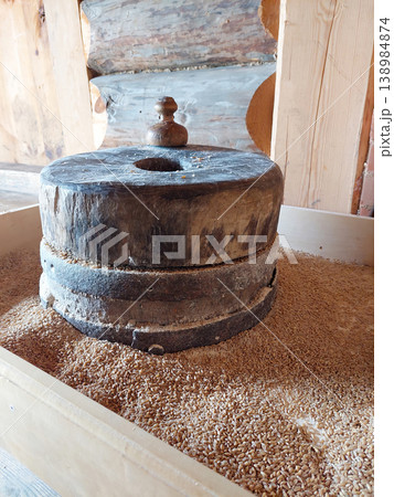 Ancient stone millstones for grinding wheat grain in a wooden barn Ancient stone millstones for grinding wheat grain in a wooden barn 138984874
