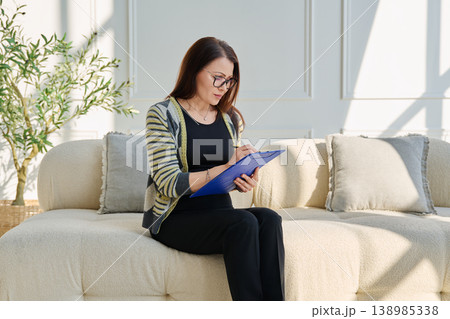 Portrait of professional psychologist therapist woman taking notes on clipboard in office Portrait of professional psychologist therapist woman taking notes on clipboard in office 138985338