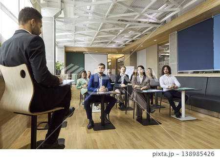 Business team listening to speaker during seminar presentation in modern office Business team listening to speaker during seminar presentation in modern office 138985426