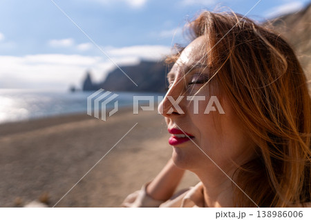 Woman beach relaxation enjoys the ocean breeze with closed eyes on a sunny coast with rocky cliffs Woman beach relaxation enjoys the ocean breeze with closed eyes on a sunny coast with rocky cliffs 138986006