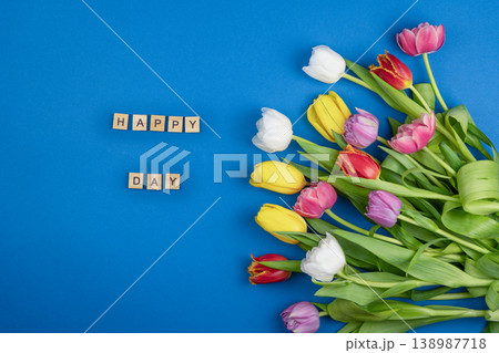 Happy Day text wooden letters Background. Tulips flowers bouquet on blue color. Happy Day text wooden letters Background. Tulips flowers bouquet on blue color. 138987718