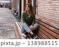 Young Woman Sitting on Wooden Bench in Urban Street Casual Lifestyle Portrait Looking Away 138988515